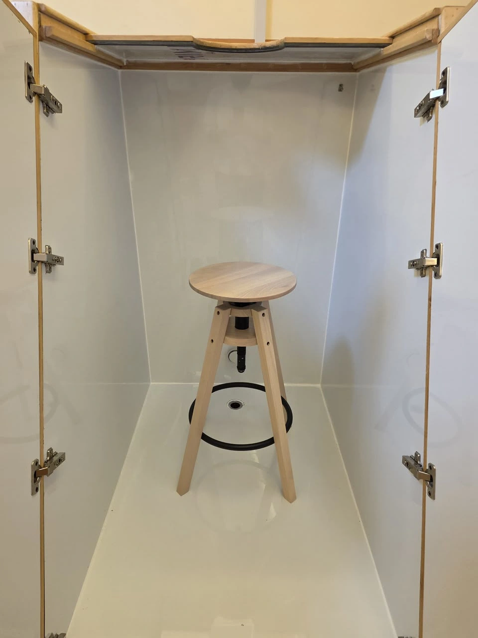 Original photograph of the open chamber with white interior, wooden stool and internal drainage